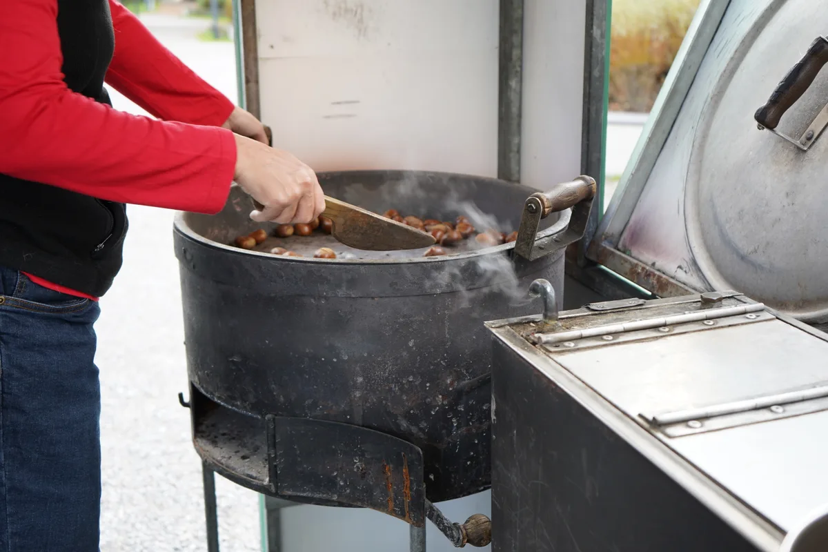 Eine Nahaufnahme von Bernets Hand, wie sie Marroni brät.